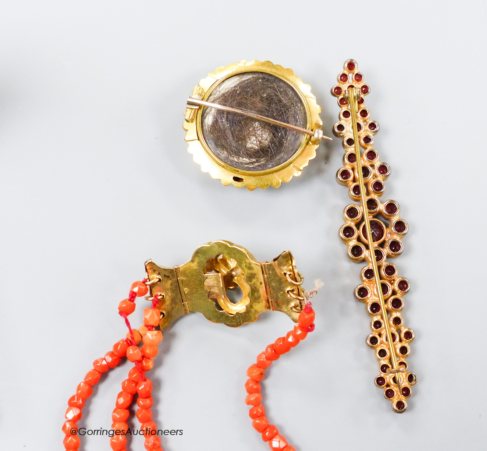 A Victorian yellow metal and banded agate set glazed back mourning brooch, 28mm, gross 8.2 grams, a paste set brooch and a facetted triple strand coral bead bracelet with yellow metal clasp(a.f.) gross 9.6 grams.